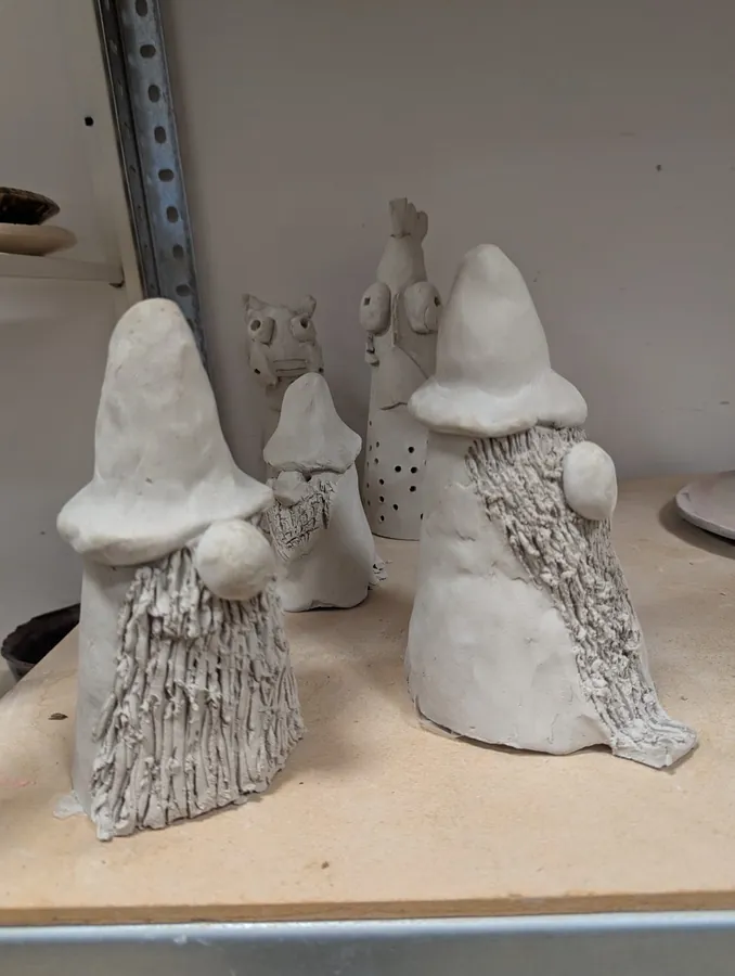 Gliniane prace uczestników ustawione na półce w pracowni ceramicznej.